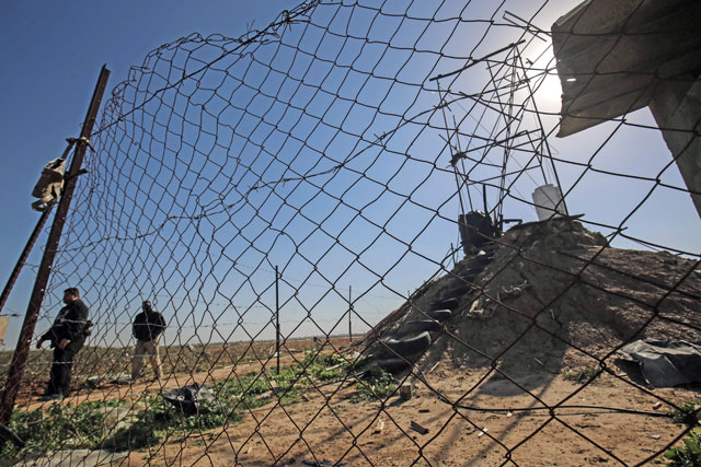 Palestinians inspect the scene of an Israeli air strike on a Hamas position during the previous night, near the town of Khan Yunis, in the southern Gaza Strip, on Monday (AFP photo)