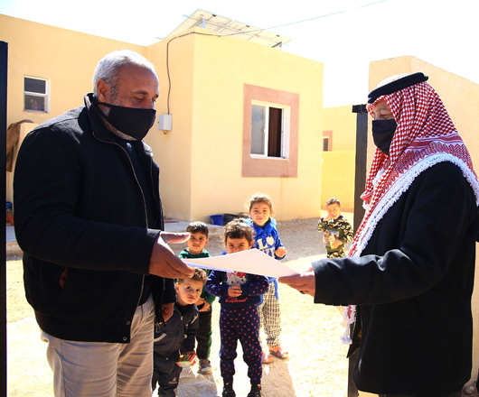 Royal Court Chief Yousef Issawi hands over documents of a new house, built as part of a Royal initiative, to a beneficiary in Ruwaished District in Mafraq on Saturday (Petra photo)