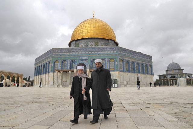 Palestinians walk outside the Dome of the Rock in Jerusalem’s Old City at Al Aqsa Mosque compound on Tuesday (AFP photo)