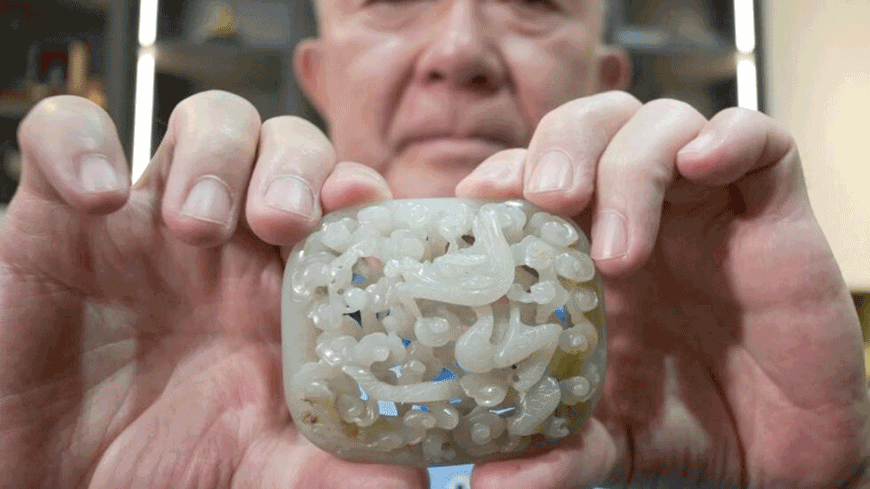 Chang Juben, chairman of Taiwan's Association of Jade Collectors, shows a Yuan dynasty jade belt ornament featuring a carving of a dragon among clouds (AFP photo)