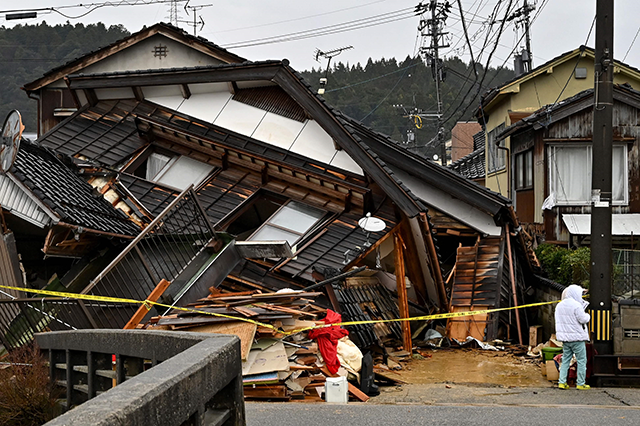 A man stands next to a collapsed house in Ishikawa prefecture on Wednesday, after a major 7.5 magnitude earthquake struck the Noto region of the prefecture on New Year's Day (AFP photo)