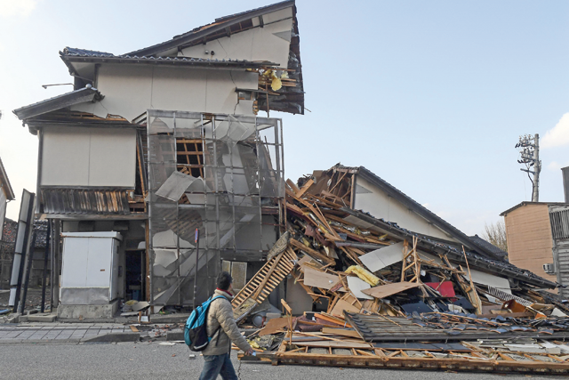 A man walks past collapsed buildings in Wajima, Ishikawa prefecture on Saturday (AFP photo)