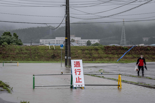 A man walks past a flooded road in the wake of ‘Typhoon No. 5’, now classified as Severe Tropical Storm Maria, in Kuji city of Iwate prefecture on Monday (AFP photo)
