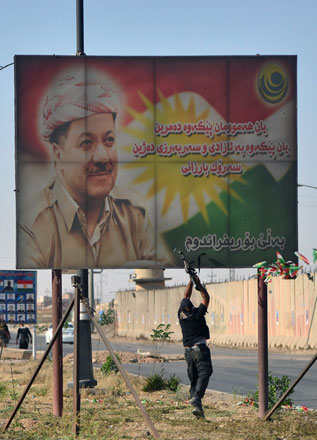 A member of Iraqi security forces shoots at a poster of Iraqi Kurdish President Massoud Barzani in Kirkuk, Iraq, on Monday (Reuters photo)