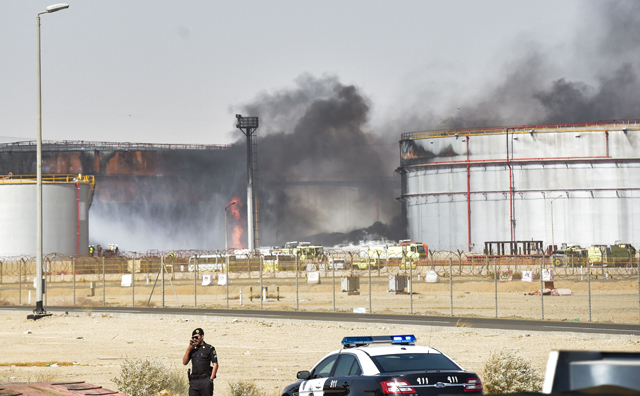 A policeman stands guard as firefighters extinguish the last hearths of fire at a Saudi Aramco oil facility in Saudi Arabia's Red Sea coastal city of Jeddah, on Saturday, a day after a Yemeni rebels attack (AFP photo)