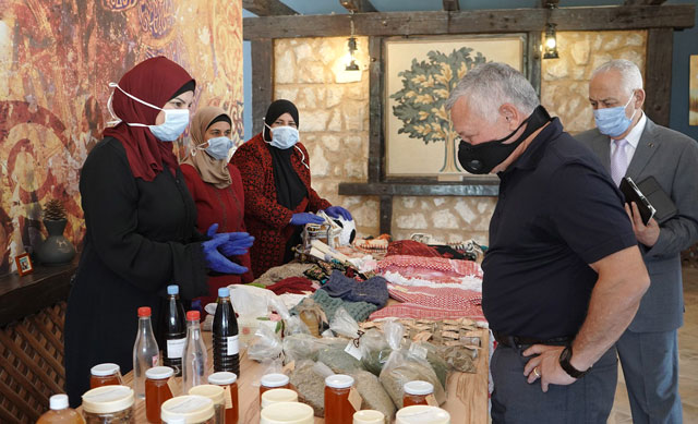 His Majesty King Abdullah tours a stall showcasing homemade products by local women during a visit to Shobak on Tuesday (Photo courtesy of Royal Court)