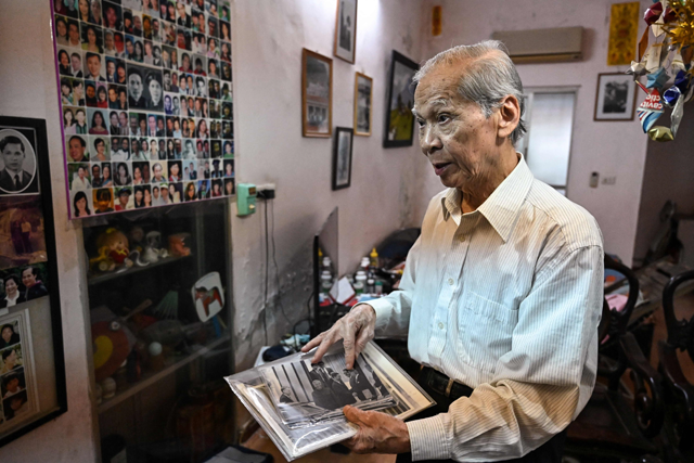 This photo taken on Friday shows Pham Ngac, a former Vietnamese diplomat and interpreter for North Vietnam’s delegation during the Paris Peace Accord negotiation, showing an old photo, featuring himself and the-then US secretary of state Henry Kissinger, at his home in Hanoi (AFP photo)