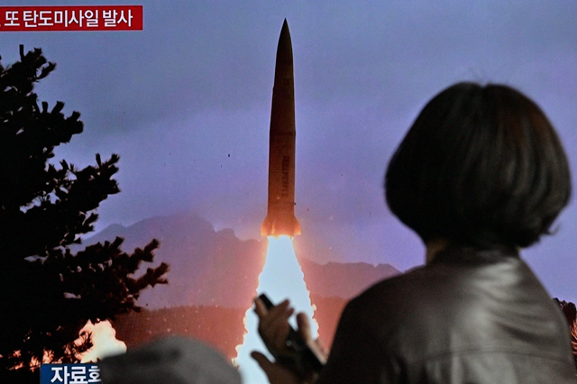 A woman walks past a television showing a news broadcast with file footage of a North Korean missile test, at a railway station in Seoul, on Sunday (AFP photo)