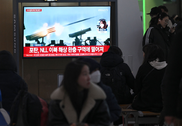 People watch a television screen showing a news broadcast with file footage of North Korea’s artillery firing, at a railway station in Seoul on Saturday (AFP photo)