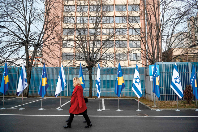Kosovo Albanians walk past Israeli's and Kosovo's flag displayed during a ceremony at the headquarters of the foreign ministry in Pristina on Monday (AFP photo)