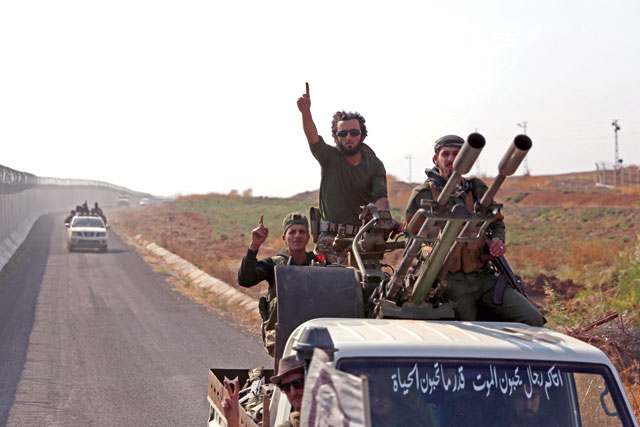 Turkey-backed Syrian fighters gesture as they travel along the border between Syria and Turkey, near the border town of Ras Al Ain in the Hassakeh province in northeastern Syria, on Sunday (AFP photo)