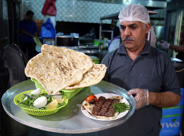 A waiter carries a tray with Iranian bread — known as taftoon — at Al Walimah restaurant in Kuwait City on June 27 (AFP photo)