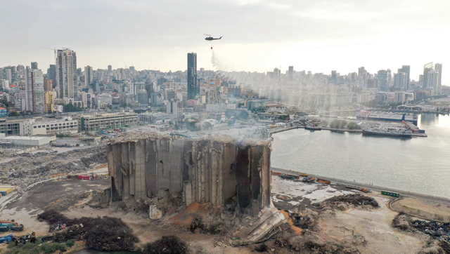An aerial photo shows a Lebanese army helicopter releasing water over the heavily damaged grain silos at the port of the capital Beirut, on Sunday, following a partial collapse due to an ongoing fire since the beginning of the month (AFP photo)