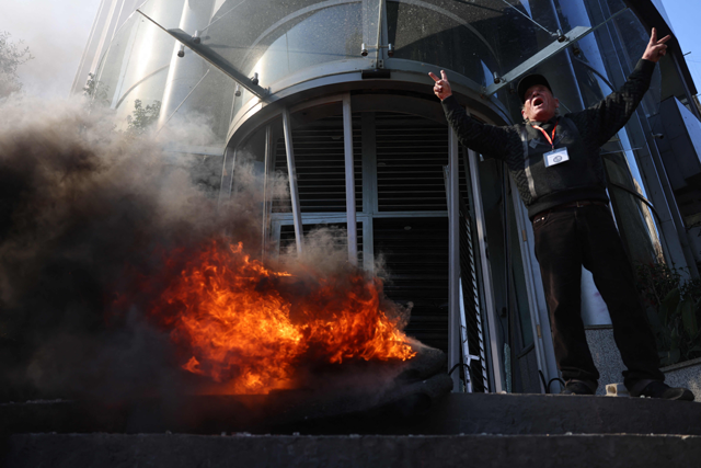 A Lebanese protester flashes the V-sign for victory and shouts slogans as others vandalise banks in Beirut on Thursday, one day after the Lebanese pound hit a record low against the dollar on the black market (AFP photo)