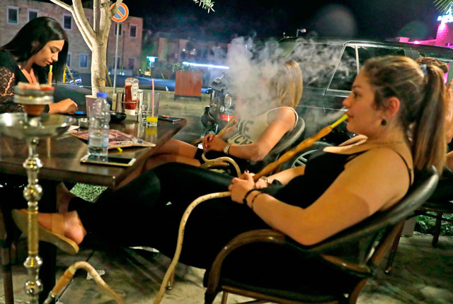 Lebanese women smoke waterpipes at a restaurant in the coastal city of Byblos north of Beirut on May 22  (AFP photo)