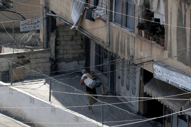 A man evacuates an elderly man near the entrance of the Ain Al Helweh Palestinian refugee camp, Lebanon’s largest Palestinian refugee camp, during clashes between Fateh movement and Islamists in the camp in the southern coastal city of Sidon on Sunday (AFP photo)
