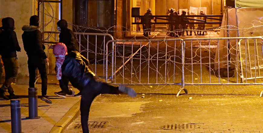 A Lebanese protester hurls stones at security forces across barricades blocking access to the parliament headquarters in the downtown district of the capital Beirut, on Wednesday, amid ongoing anti-government demonstrations (AFP photo)