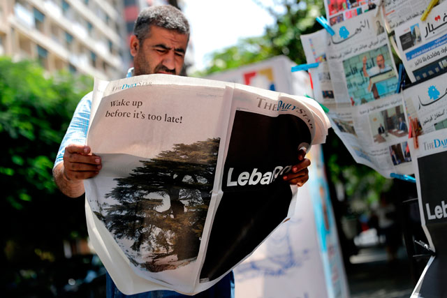 This file photo taken on August 08, 2019, shows a man checking a copy of the Lebanese local English-language newspaper ‘The Daily Star’ in the capital Beirut (AFP photo)