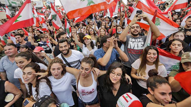 Lebanese demonstrators wave national flags on a highway linking Beirut to north Lebanon, in Zouk Mikael  (AFP photo)