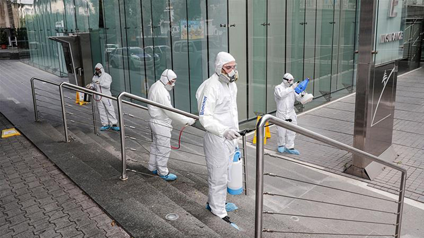 Employees of a private company spray sanitising liquid around a bank to limit the spread of the coronavirus in the Lebanese capital Beirut in April (AFP photo)
