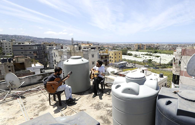 Lebanese musician Ziad Al Zayyat (left) and his flat mate, interior designer Saad Molaeb, play their guitars on the rooftop of their building in the town of Hadath on Tuesday (AFP photo)