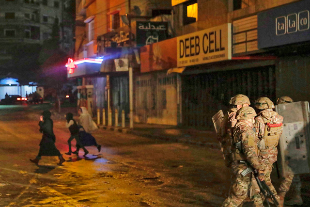 People cross the street as security forces advance during clashes with anti-government protesters in the northern city of Tripoli, on Friday  (AFP photo)
