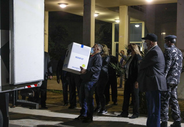 Members of Lebanese security forces and staff look on during the unloading of boxes of the first shipment of the COVID-19 Pfizer-BioNTech vaccine, upon arrival to the Rafik Hariri Hospital in the capital Beirut, on Saturday (AFP photo)