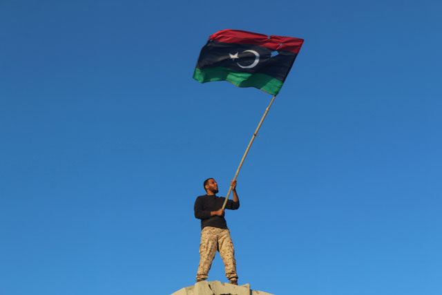 A fighter of Libyan forces holds a Libyan flag as he celebrates after forces finished clearing Ghiza Bahriya, the final district of the former Daesh stronghold of Sirte, Libya, on Tuesday (Reuters photo)
