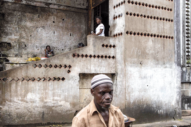 Banana vendors are seen outside an entrance to the derelict E.J Roye skyscraper in Monrovia on Wednesday (AFP photo)