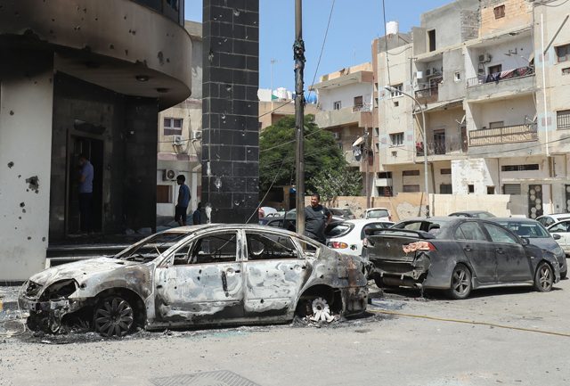 People inspect car carcasses in front of a damaged building following clashes between backers of rival governments in Libya's capital Tripoli, on Sunday (AFP photo)