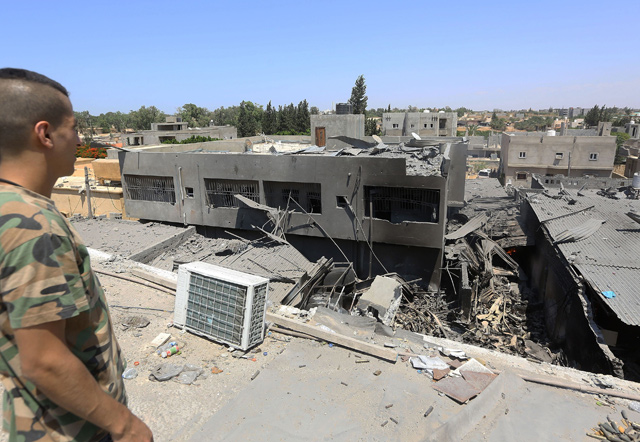 A fighter loyal to the Libyan Government of National Accord forces checks the ruins of a building near the the Yarmouk military compound, following air strikes south of the Libyan capital Tripoli, on Monday  (AFP photo)