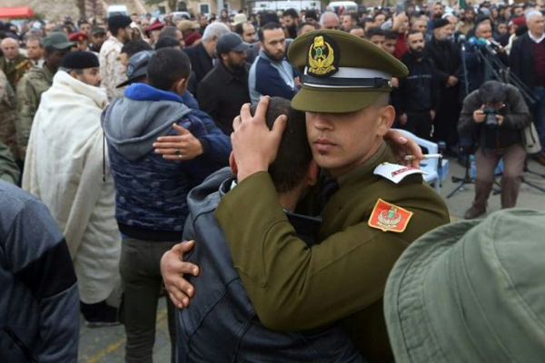 Libyan console each other during a funeral ceremony for some 30 army cadets killed in an air strike on a military school in Tripoli  (AFP photo)
