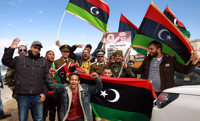 Libyans wave national flags as they gather to mark the 10th anniversary of the 2011 revolution, in the eastern city of Benghazi, on Wednesday (AFP photo)