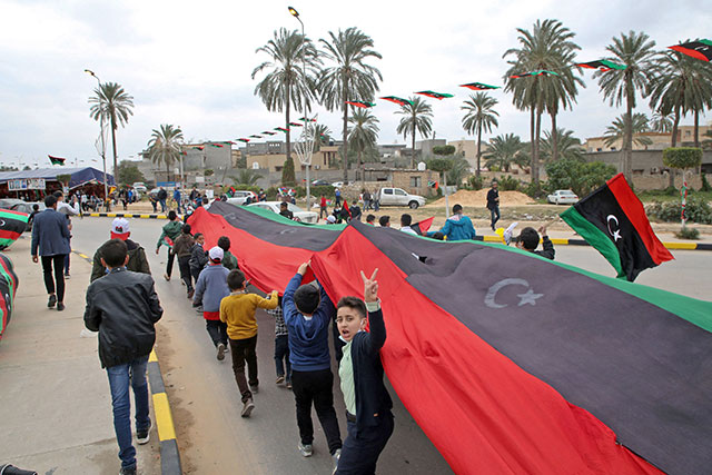 Libyan youth march with a giant national flag in the capital Tripoli on Thursday during celebrations commemorating the 10th anniversary of the 2011 revolution that toppled longtime dictator Muammar Qadhafi (AFP photo)