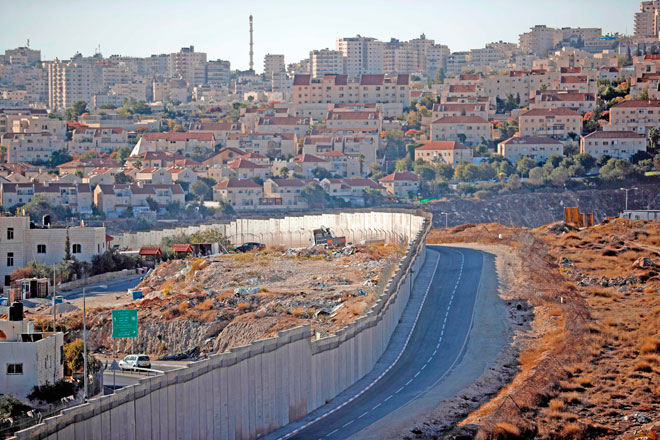 Israel's controversial separation barrier is seen dividing Jerusalem (background) from the West Bank town of Hizma (left),  on Thursaday (AFP photo)