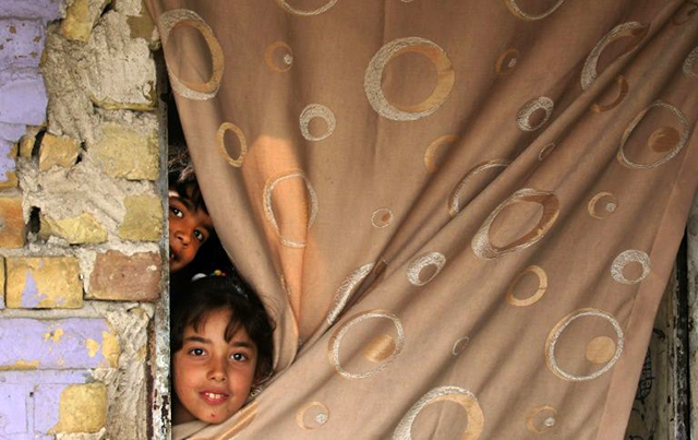 Iraqi children peek out of their Baghdad home during a disinfection campaign to stem the spread of the novel coronavirus (AFP photo)