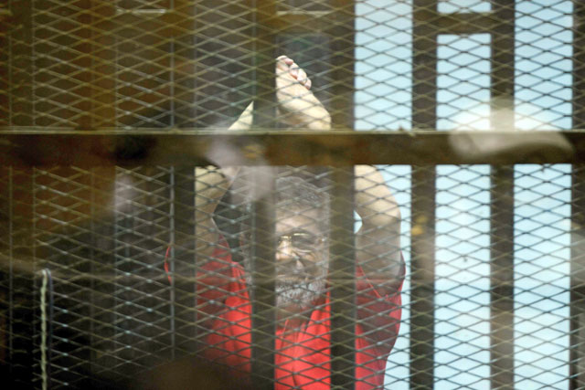 This file photo taken on June 18, 2016, shows Egypt’s ousted Islamist president Mohamed Morsi, wearing a red uniform, gesturing from behind the defendant’s bars during his trial on espionage charges at a court in Cairo (AFP photo)