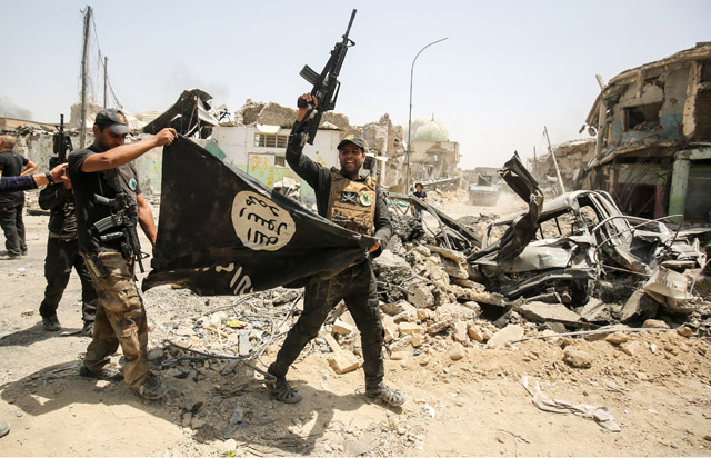 Members of the Iraqi Counter-Terrorism Service cheer as they carry upside-down a black flag of the Daesh group, with the destroyed Al Nuri Mosque seen in the background, in the Old City of Mosul on Sunday, during the offensive to retake the city from Daesh fighters (AFP photo)