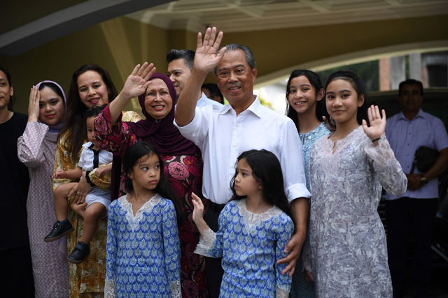 Malaysia’s former interior minister Muhyiddin Yassin (centre) and his family wave to the press outside his home in Kuala Lumpur on Saturday (AFP photo)