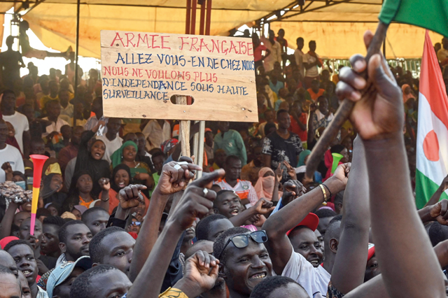 A supporter of Niger’s National Council of Safeguard of the Homeland (CNSP) holds a sign that reads,’French army lave us, we don’t want any more independence under high surveillance’, as people protest outside the Niger and French airbase to demand the departure of the French army from Niger, in Niamey, on Saturday (AFP photo)