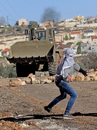 A Palestinian protester throws stones at Israeli forces during a protest against land expropriations by Israeli government at Kafr Kaddum village of Nablus, West Bank, on Friday (Anadolu Agency photo)