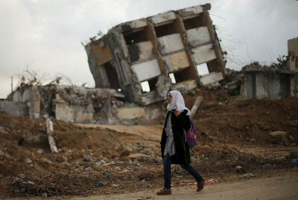A Palestinian schoolgirl walks past the remains of a house destroyed during the 2014 Israeli aggression as she returns to her home on a winter day in the northern Gaza Strip on Wednesday (Reuters photo)