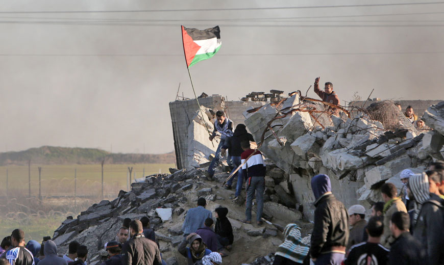 A Palestinian protester holds a national flag during confrontations with Israeli forces along the border with Israel in the eastern suburbs of Gaza City on Friday (AFP photo)