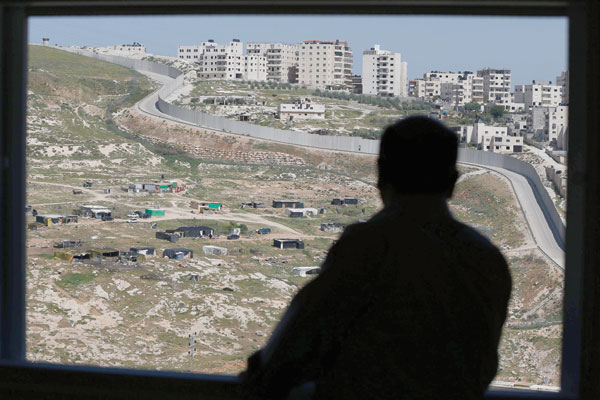 A man looks from his window at the controversial  Israeli separtion barrier surrounding the East Jerusalem neighbourhood of Shuafat (in the background) on Thursday at his home in the East Jerusalem Arab neighbourhood of Issawiya (AFP photo)