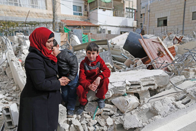 Palestinian children and their mother, from the Abu Ramouz family, sit on the rubble of their house that was demolished by Israeli army bulldozers in the Arab East Jerusalem neighbourhood of Beit Hanina on Wednesday on the grounds that it was built without a construction permit (AFP photo)