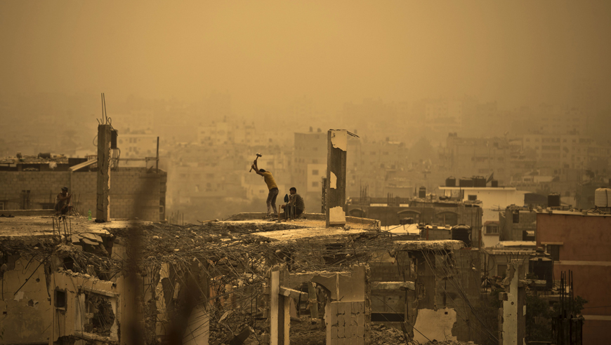 A general view of Gaza City shows Palestinian workers removing debris from buildings which were destroyed during the 50-day war between Israel and Hamas fighters in the summer of 2014, amid a sandstorm on Tuesday (AFP photo)