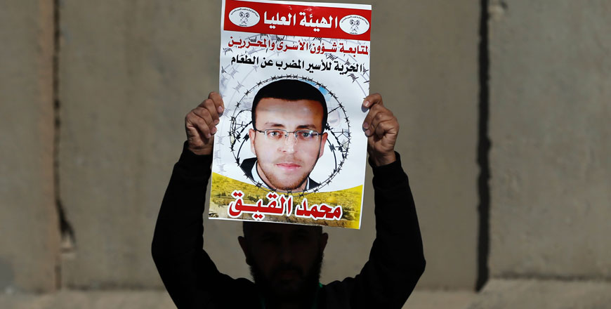 This file photo taken on January 22, 2016 shows a Palestinian man carrying a placard bearing a portrait of Palestinian journalist Mohammed Al Qiq, during a demonstration demanding his release from an  Israeli jail, next to a Jewish settlement north of Ramallah (AFP photo)