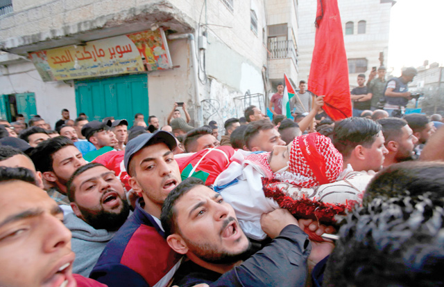 Palestinian mourners carry the body of Omar Al Badawi, who was killed earlier in the day during confrontations with Israeli forces in Al Arroub refugee camp, during his funeral on Monday, in the Israeli-occupied West Bank (AFP photo)