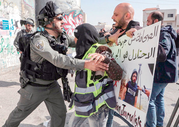 An Israeli soldier scuffles with Palestinian journalists gathering during a demonstration alongside Israel's separation barrier in Bethlehem in the occupied West Bank on Sunday (AFP photo)