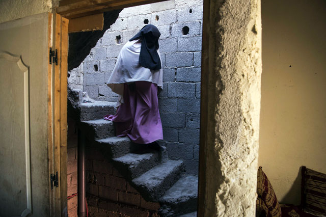 Fatima El Khayali, the aunt of Abdelrahim El Khayali, one of the suspects who were arrested following the murder of two Scandinavian hikers in Morocco's High Atlas Mountains, descends the stairs of her house in the neighbourhood of Azzouzia in  Marrakesh on Friday (AFP photo)